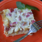 orange plate with square of rhubarb kuchen and a fork