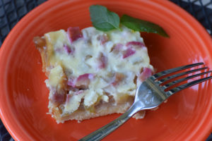 orange plate with square of rhubarb kuchen and a fork